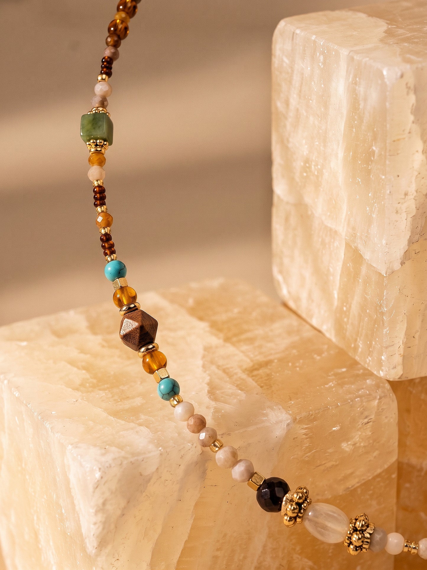 Détail des perles ambre, vert et turquoise du collier pendentif soleil SOLSTICE.