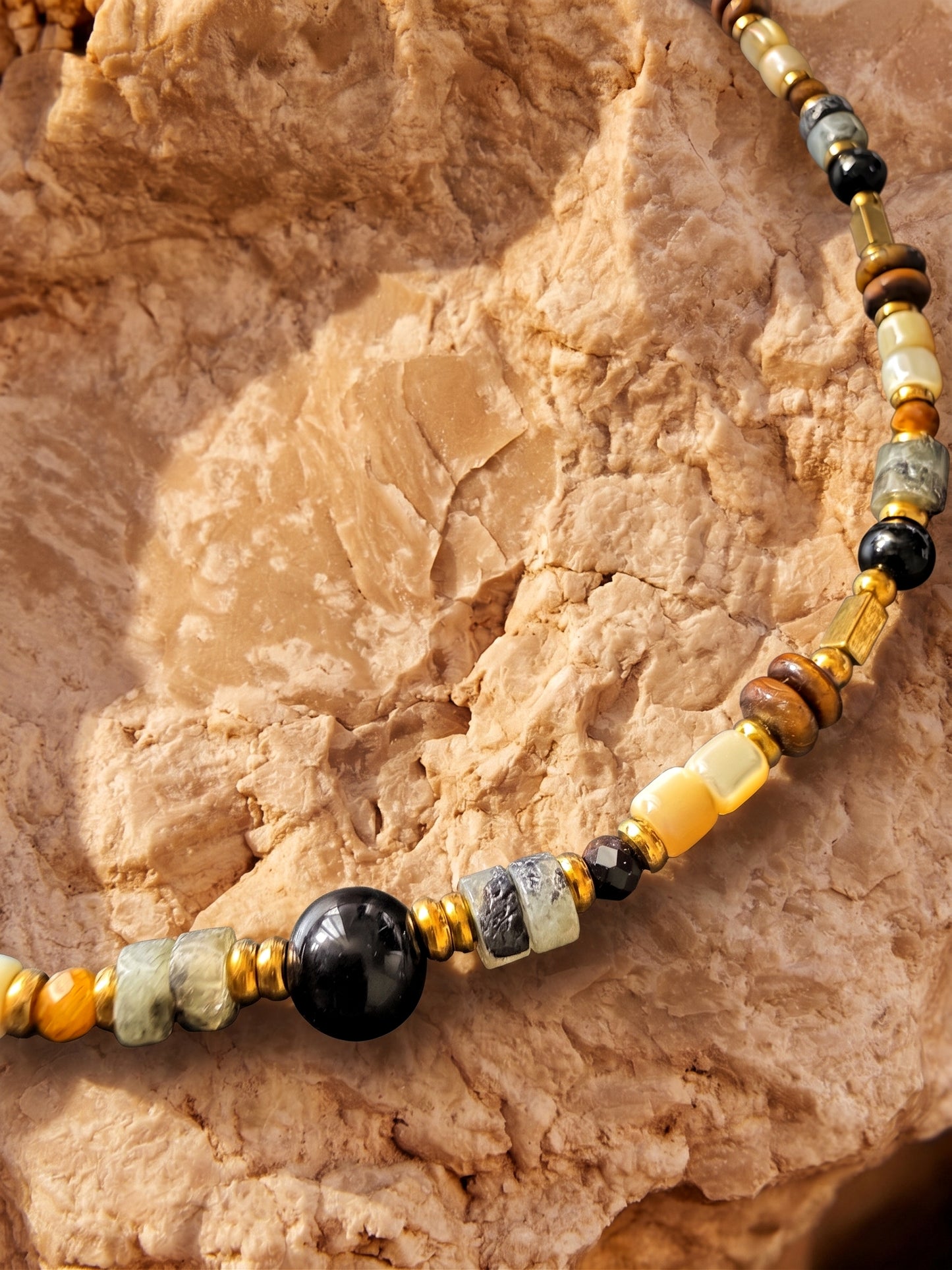 Femme portant le collier ras de cou BOIS DE NUIT, bijou bohème chic avec pendentif Œil de tigre et agate noire.