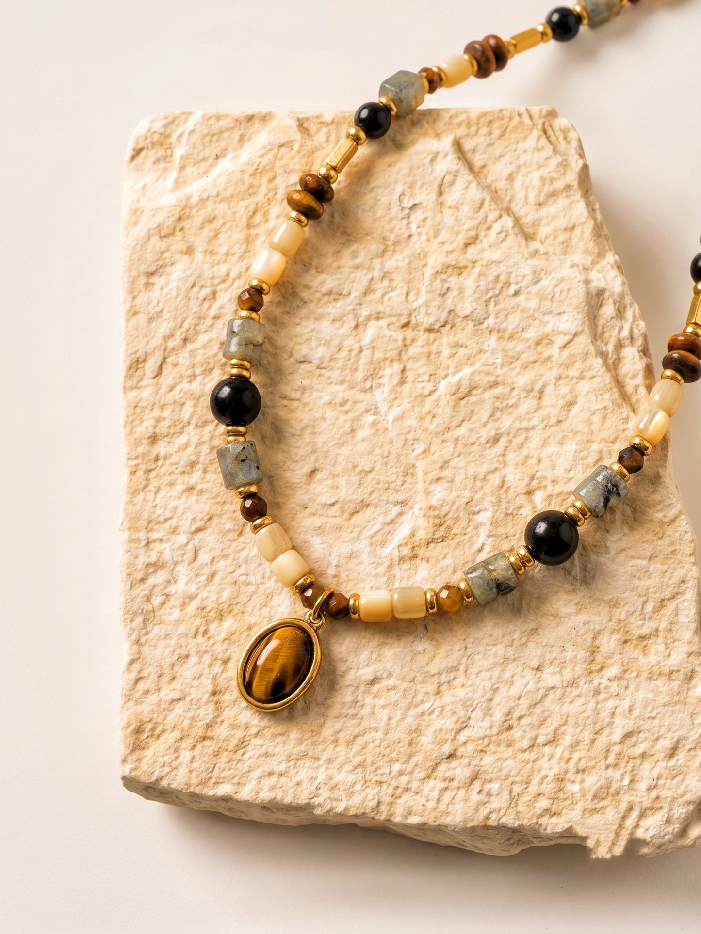Femme portant le collier ras de cou BOIS DE NUIT, bijou bohème chic avec pendentif Œil de tigre et agate noire.