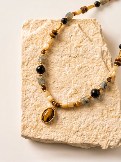 Femme portant le collier ras de cou BOIS DE NUIT, bijou bohème chic avec pendentif Œil de tigre et agate noire.
