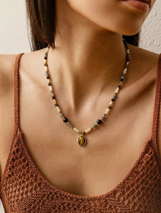 Femme portant le collier ras de cou BOIS DE NUIT, bijou bohème chic avec pendentif Œil de tigre et agate noire.