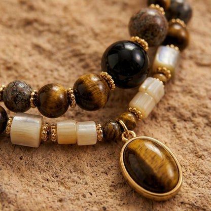 Détail en gros plan des pierres naturelles (Œil de tigre, Labradorite) et du pendentif doré du collier BOIS DE NUIT.